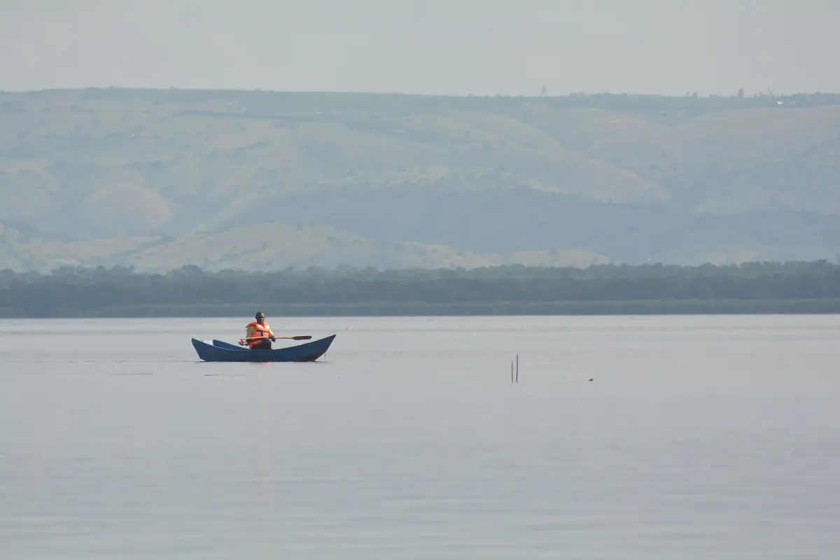 Fisherman paddling a small canoe on calm Lake Mburo