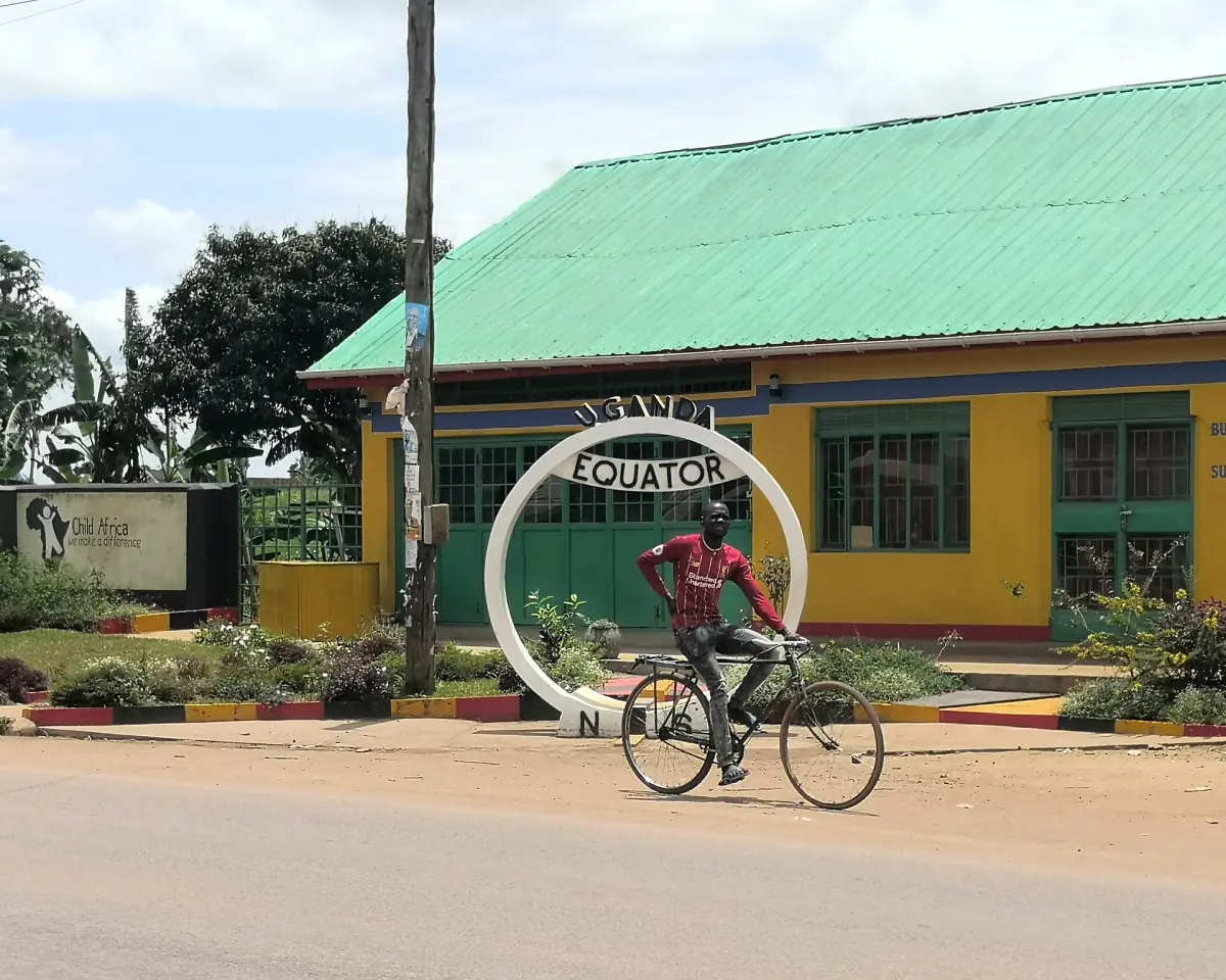 Equator ring beside a green roofed building with a passing cyclist
