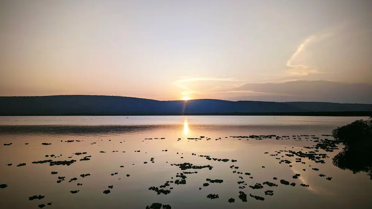 Sun setting over Lake Mburo with hills along the far shore