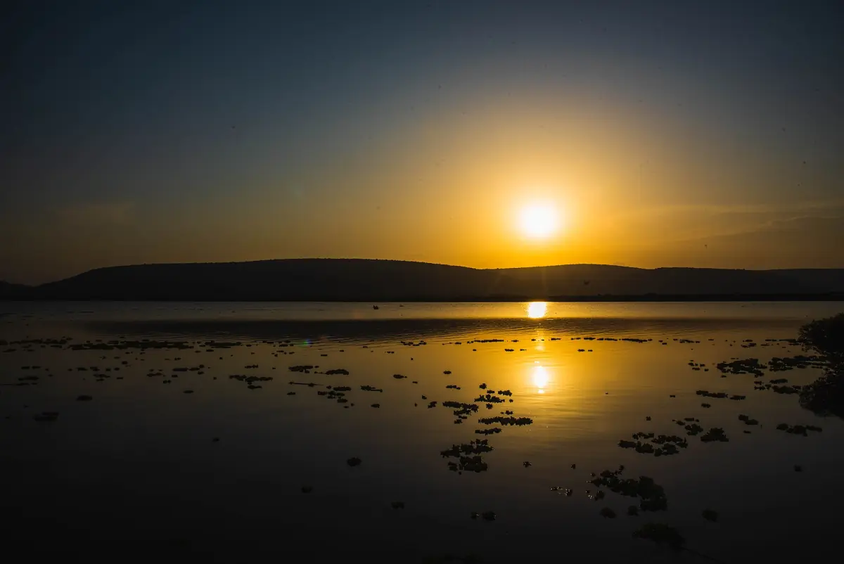 Oranje zonsondergang boven het meer met het silhouet van de Kigarama Hills